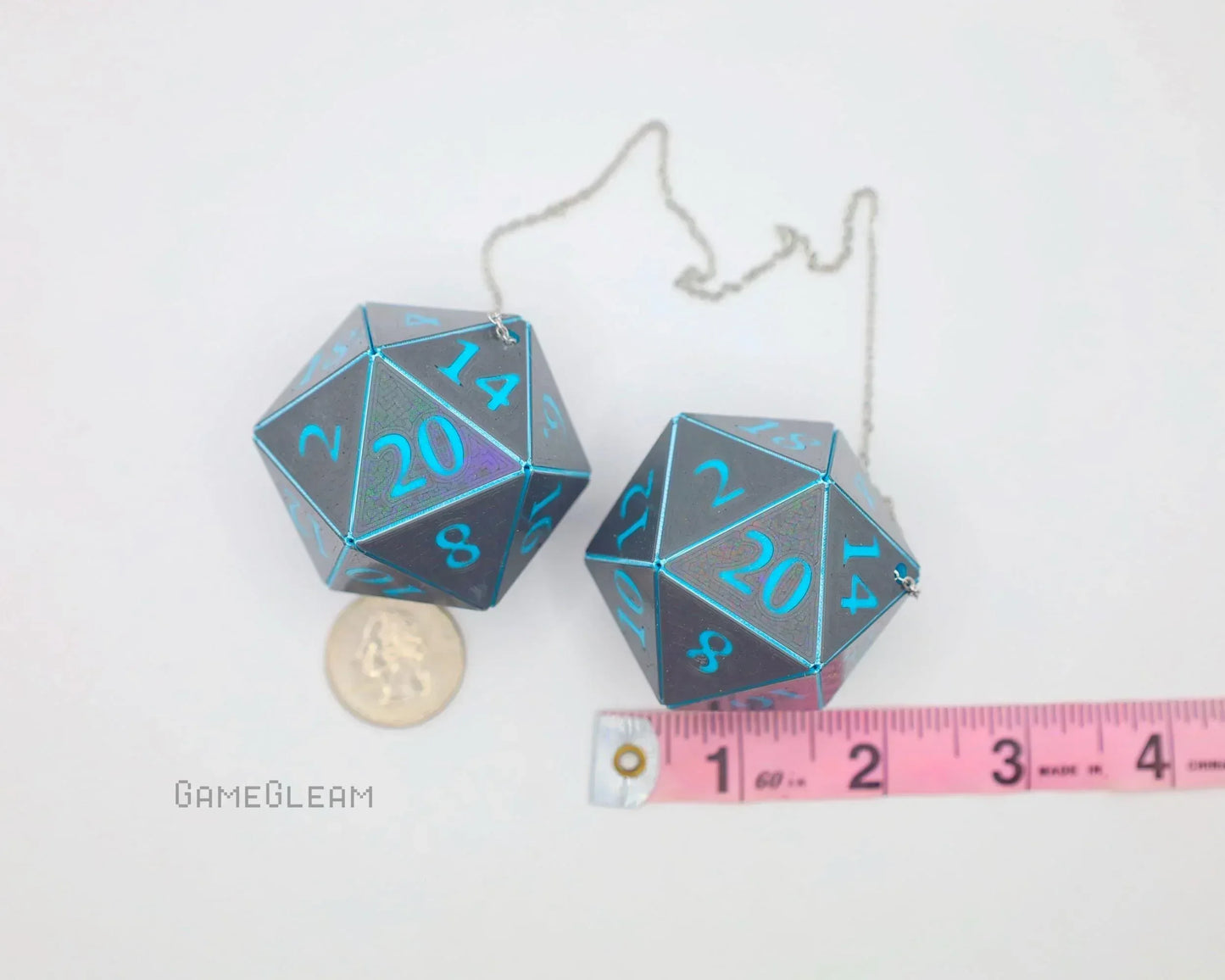 Pair of holographic 20-sided dice car charms with blue numbers, shown with ruler and coin for scale.