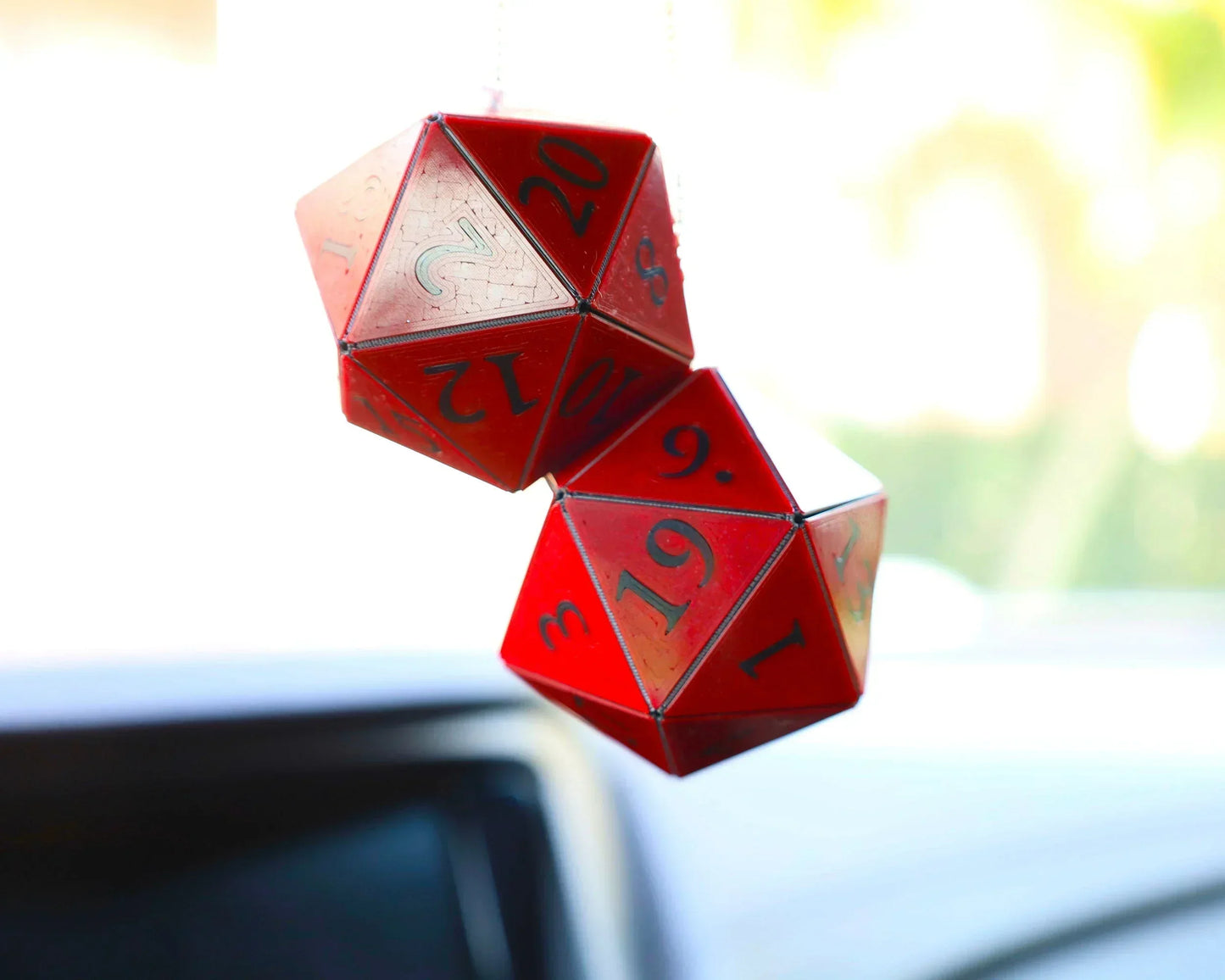 Red handmade twenty-sided dice car charm hanging from a rearview mirror.