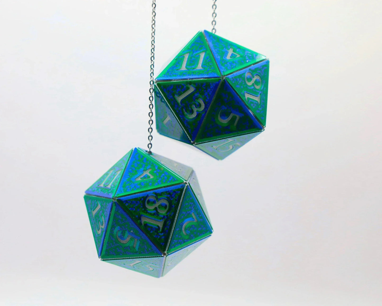 Holographic blue and green twenty-sided dice hanging from chains, gamer car accessory.