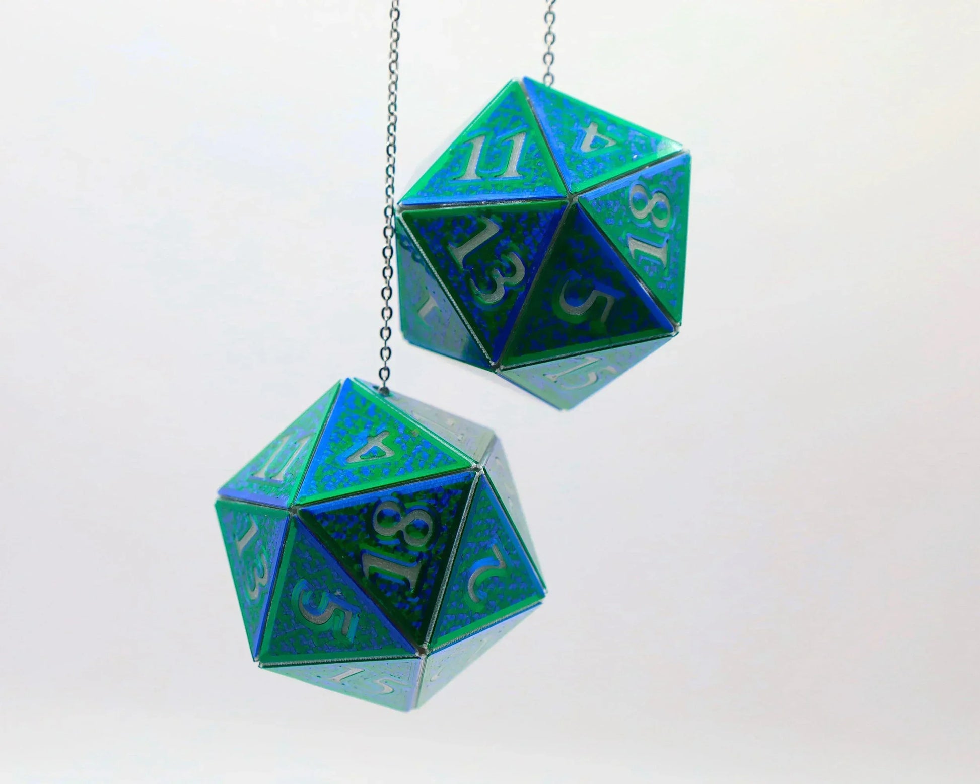 Holographic blue and green twenty-sided dice hanging from chains, gamer car accessory.