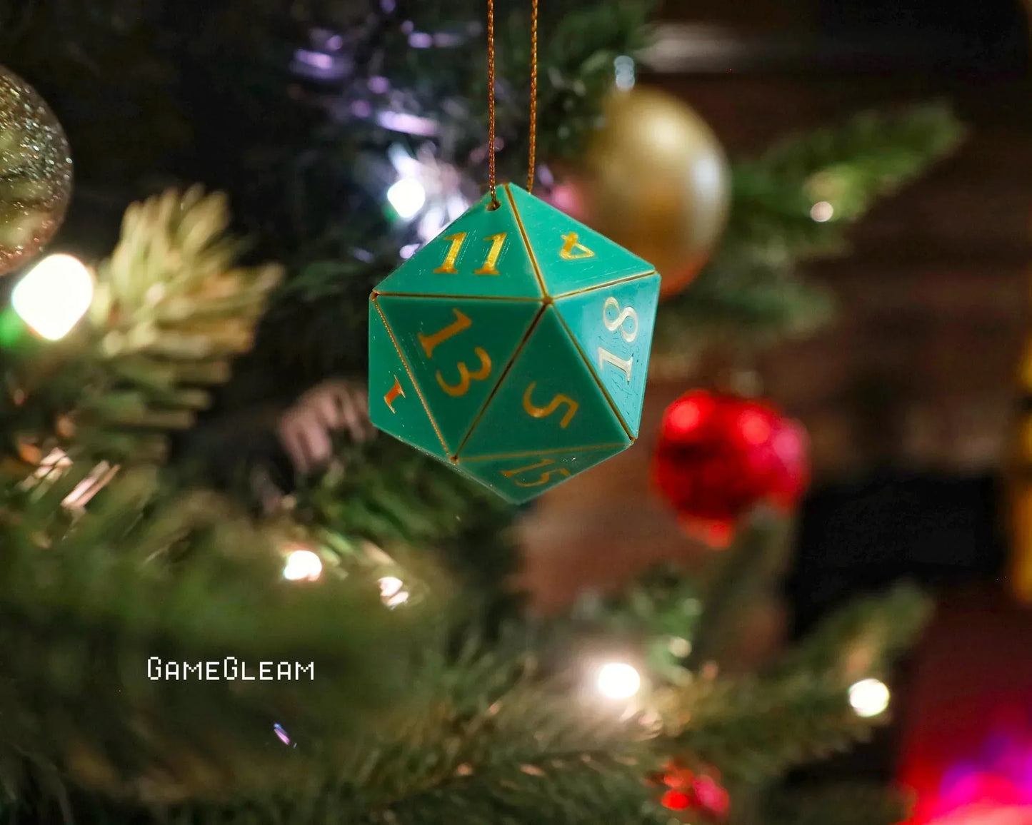 Teal 20-sided dice ornament hanging on a decorated Christmas tree with festive lights.