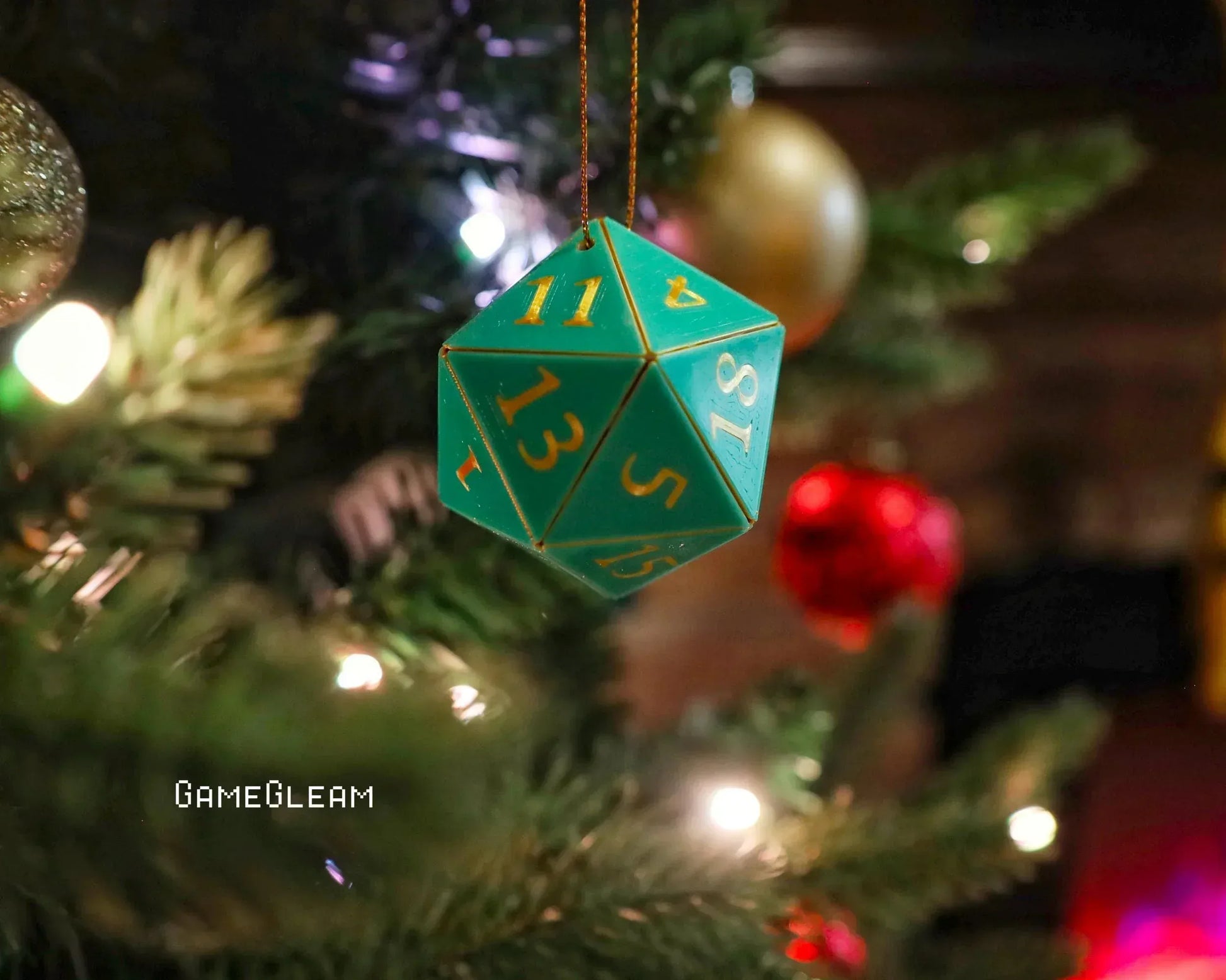 Teal 20-sided dice ornament hanging on a decorated Christmas tree with festive lights.