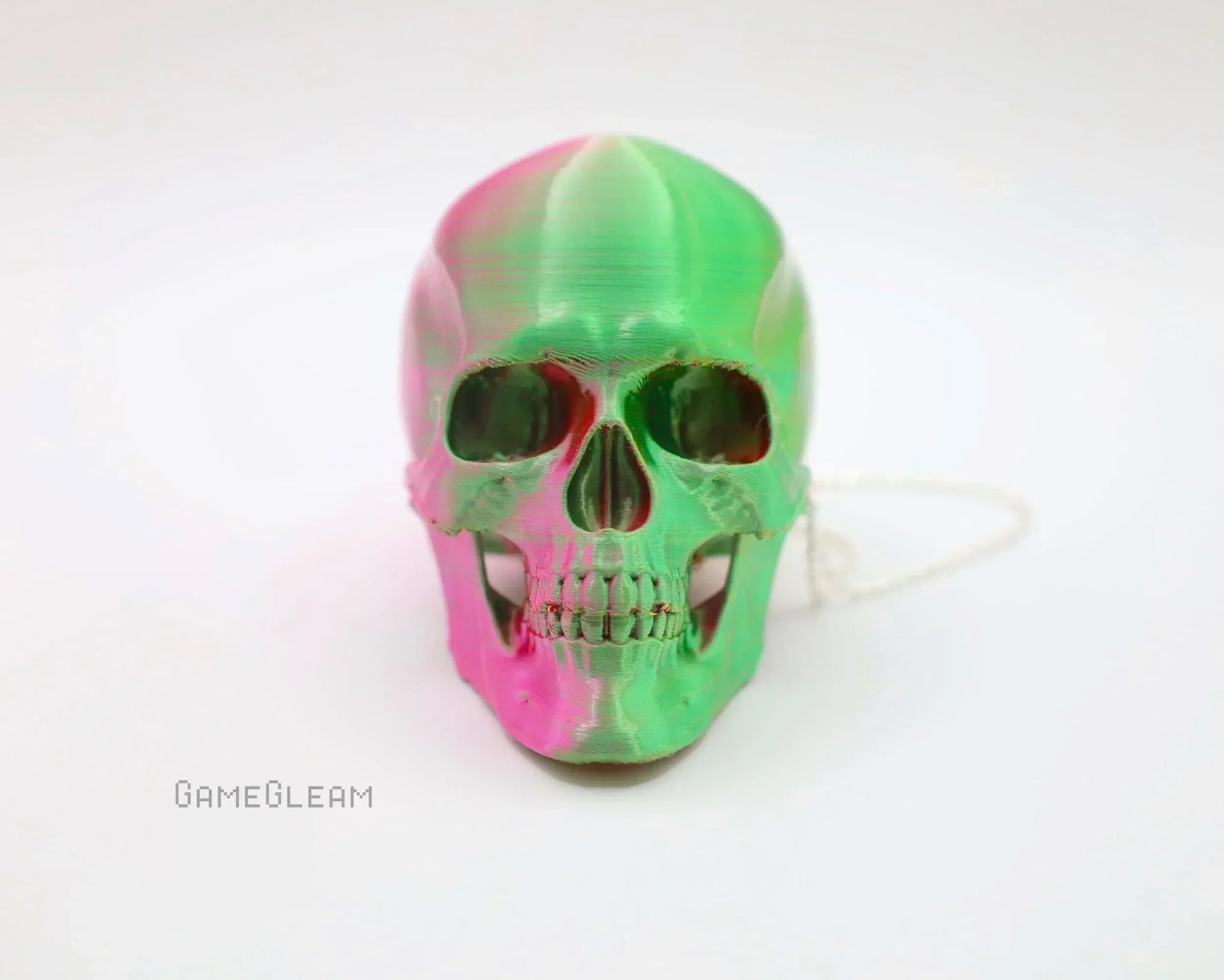 Handmade green and pink resin skull decor with chain on white background
