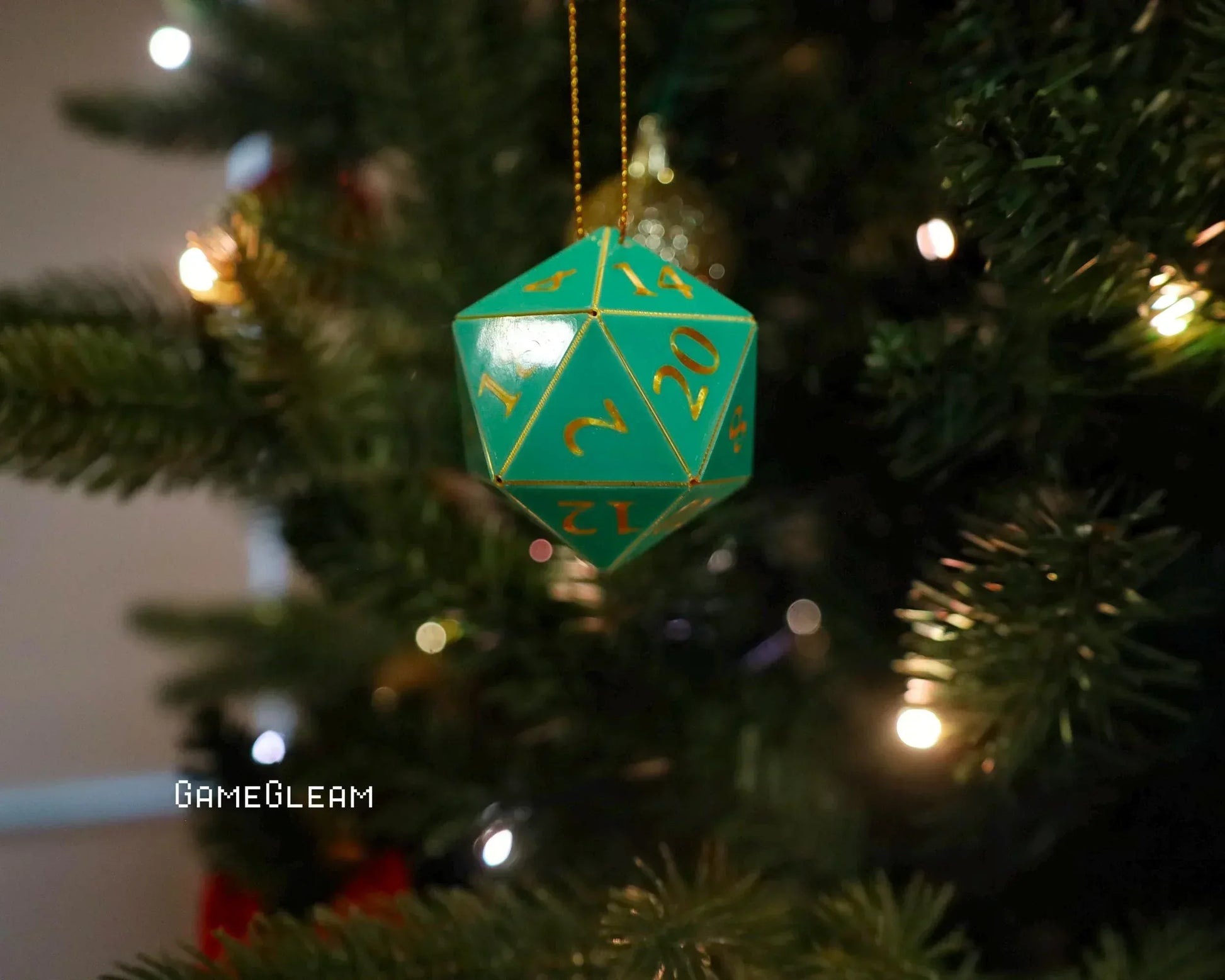 Green twenty-sided dice ornament with gold numbers hanging on a Christmas tree