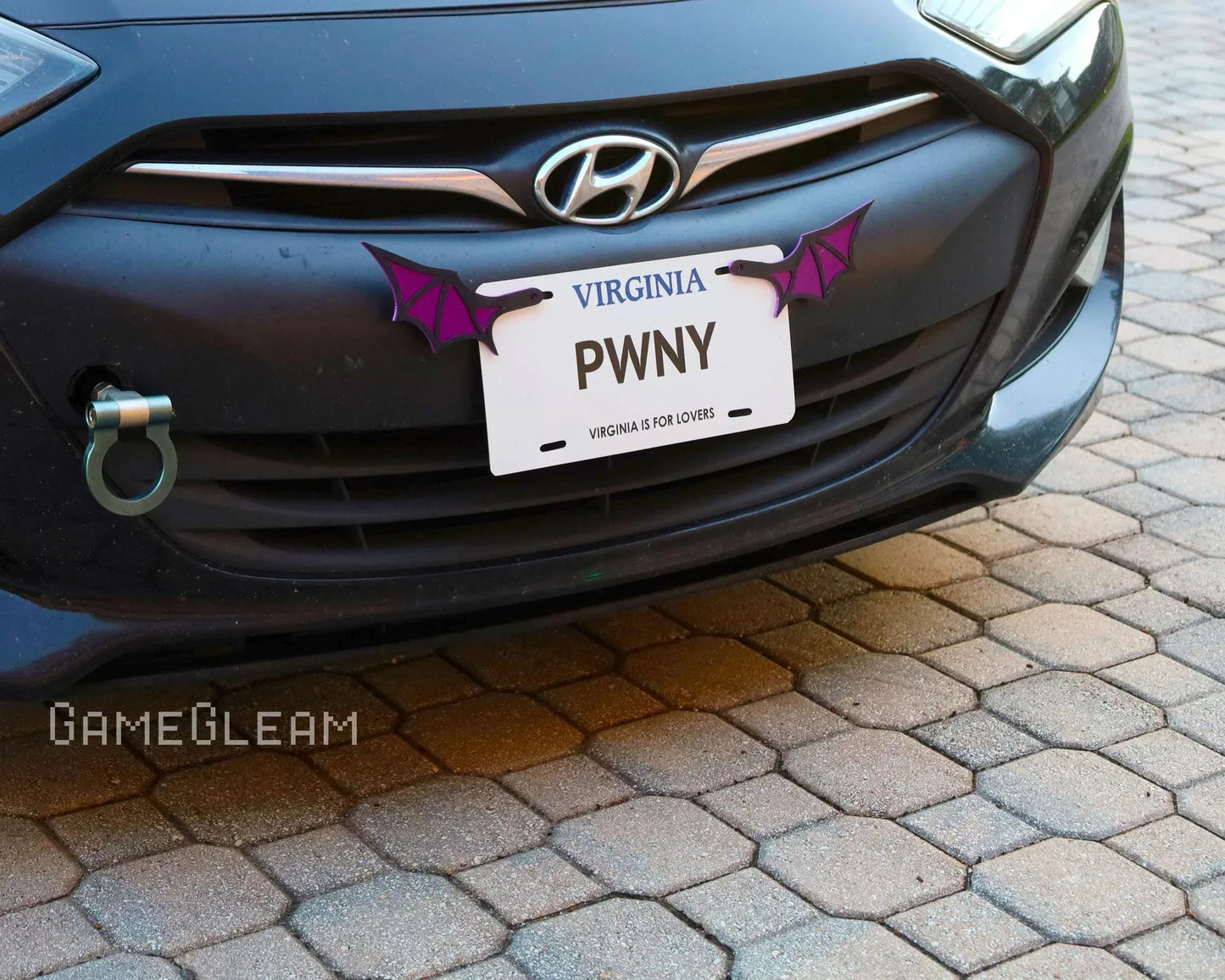 Front of Hyundai car with custom license plate featuring purple bat wing decorations.