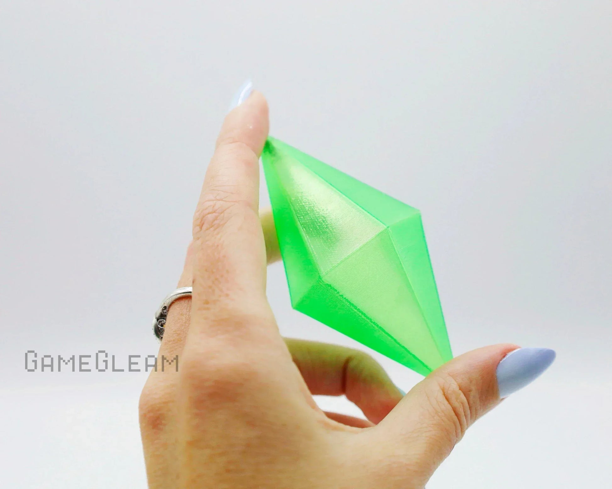 Hand holding a bright green crystal-shaped car charm accessory with a silver ring visible