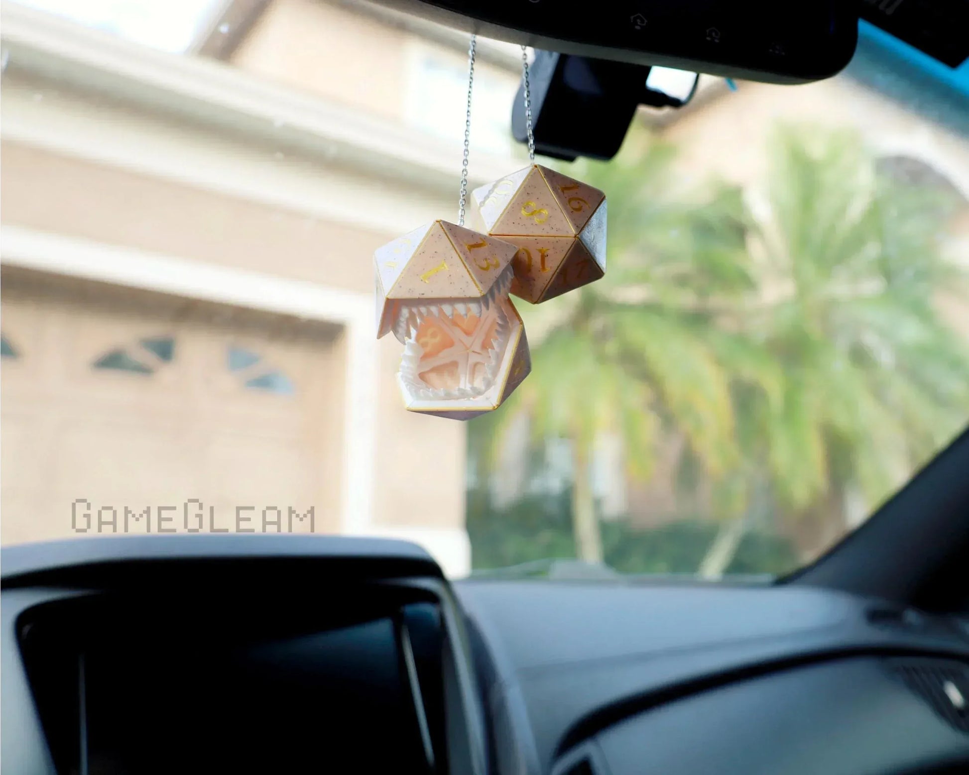 Handmade polyhedral dice car charm with dragon mouth detail hanging in a car interior