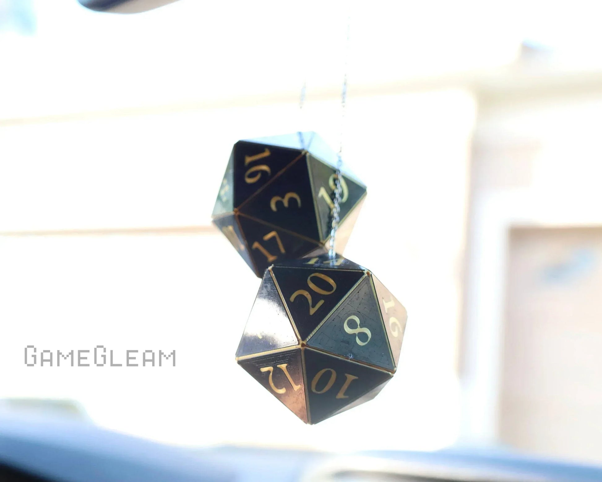 Holographic twenty-sided dice car charm hanging from rearview mirror, metallic numbers visible.