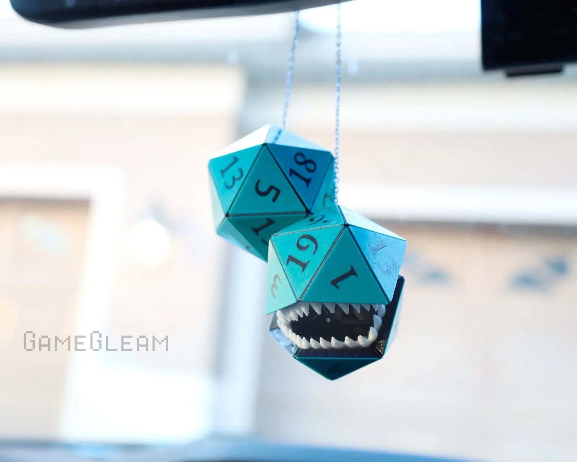 Handmade teal twenty-sided dice car charm with monster mouth, hanging from rearview mirror.