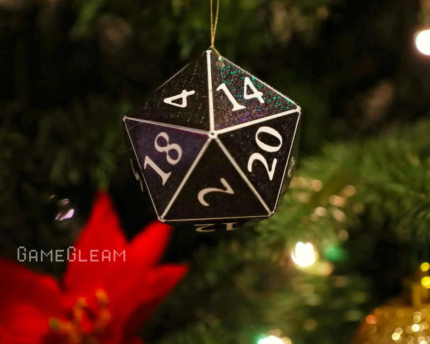 Black glittery twenty-sided dice ornament hanging on a Christmas tree with festive lights.