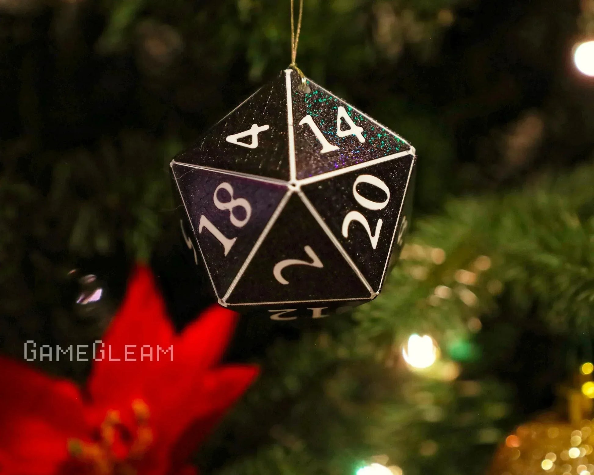 Black glittery twenty-sided dice ornament hanging on a Christmas tree with festive lights.