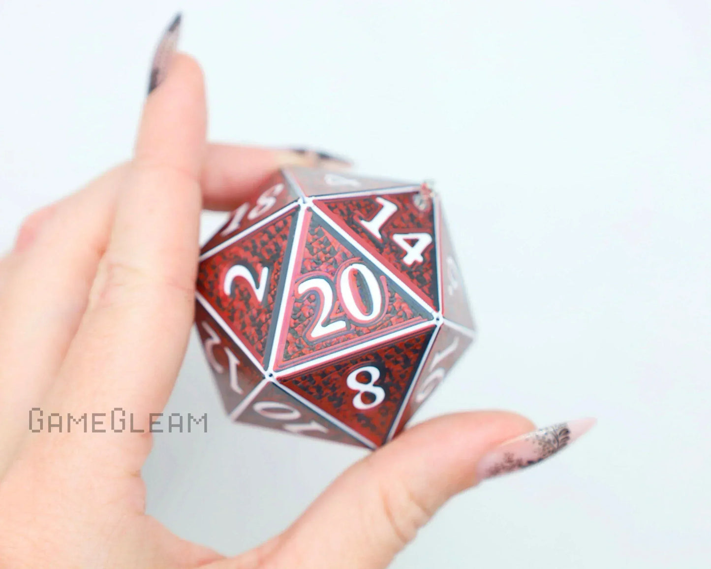 Hand holding a red and black holographic twenty-sided dice with white numbers, gamer gift