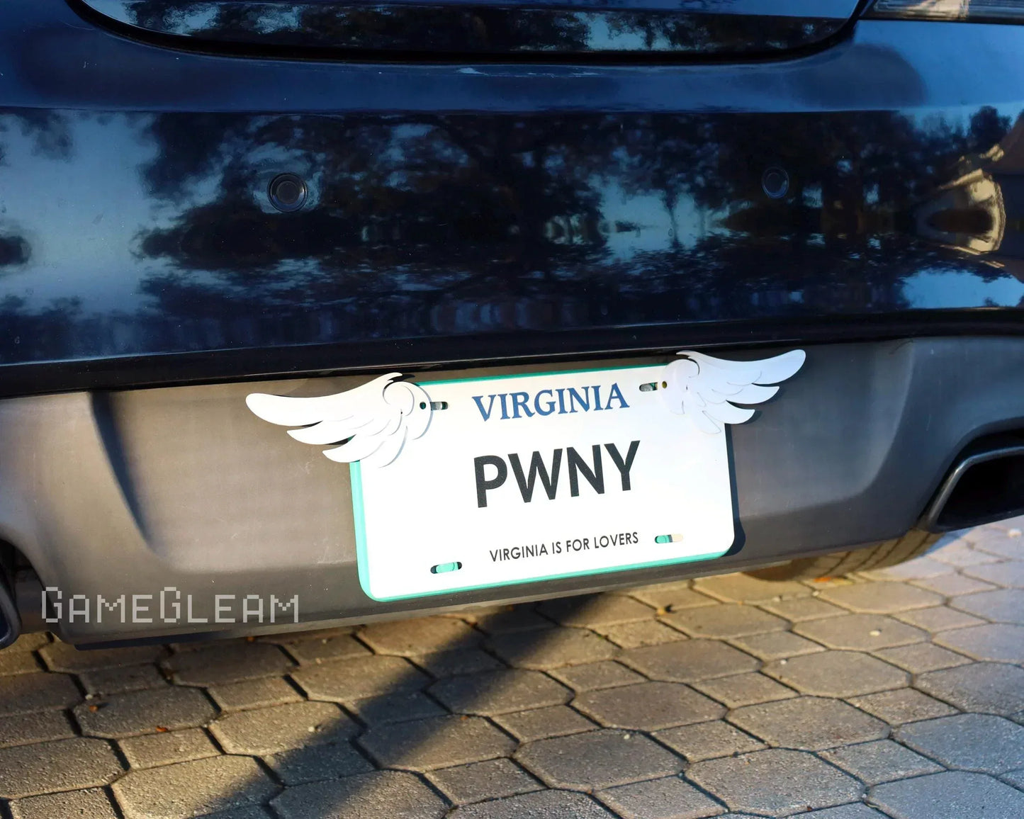 Virginia car license plate with white wing decals on both sides, parked on cobblestone.