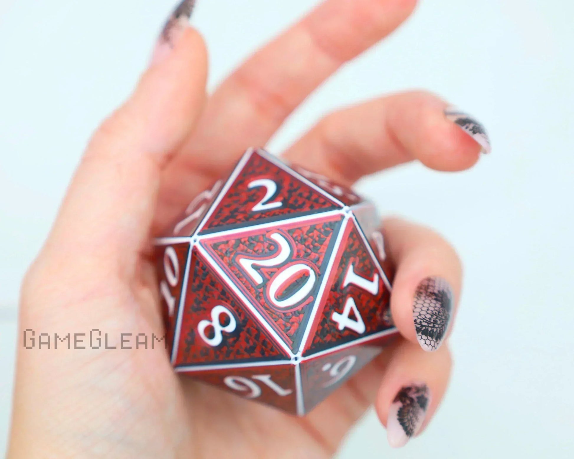 Hand holding large red and black twenty-sided dice with white numbers, gamer accessory