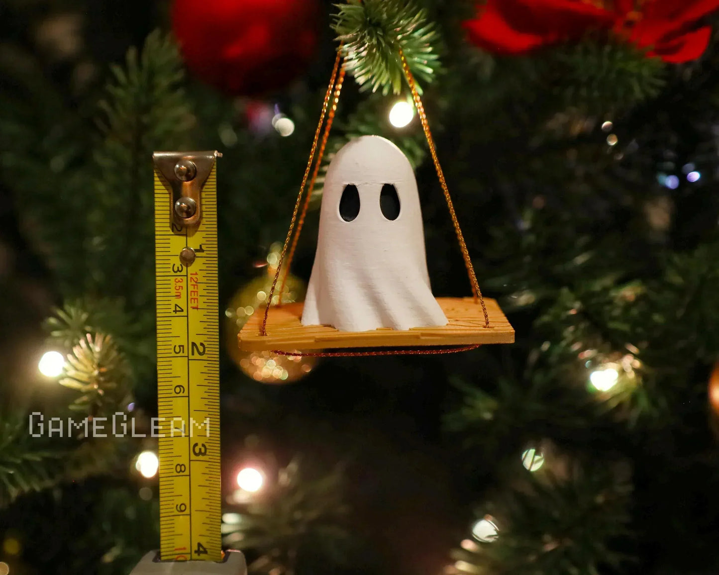 Handmade ghost ornament on a wooden swing, measured beside a tape, hanging on a holiday tree.