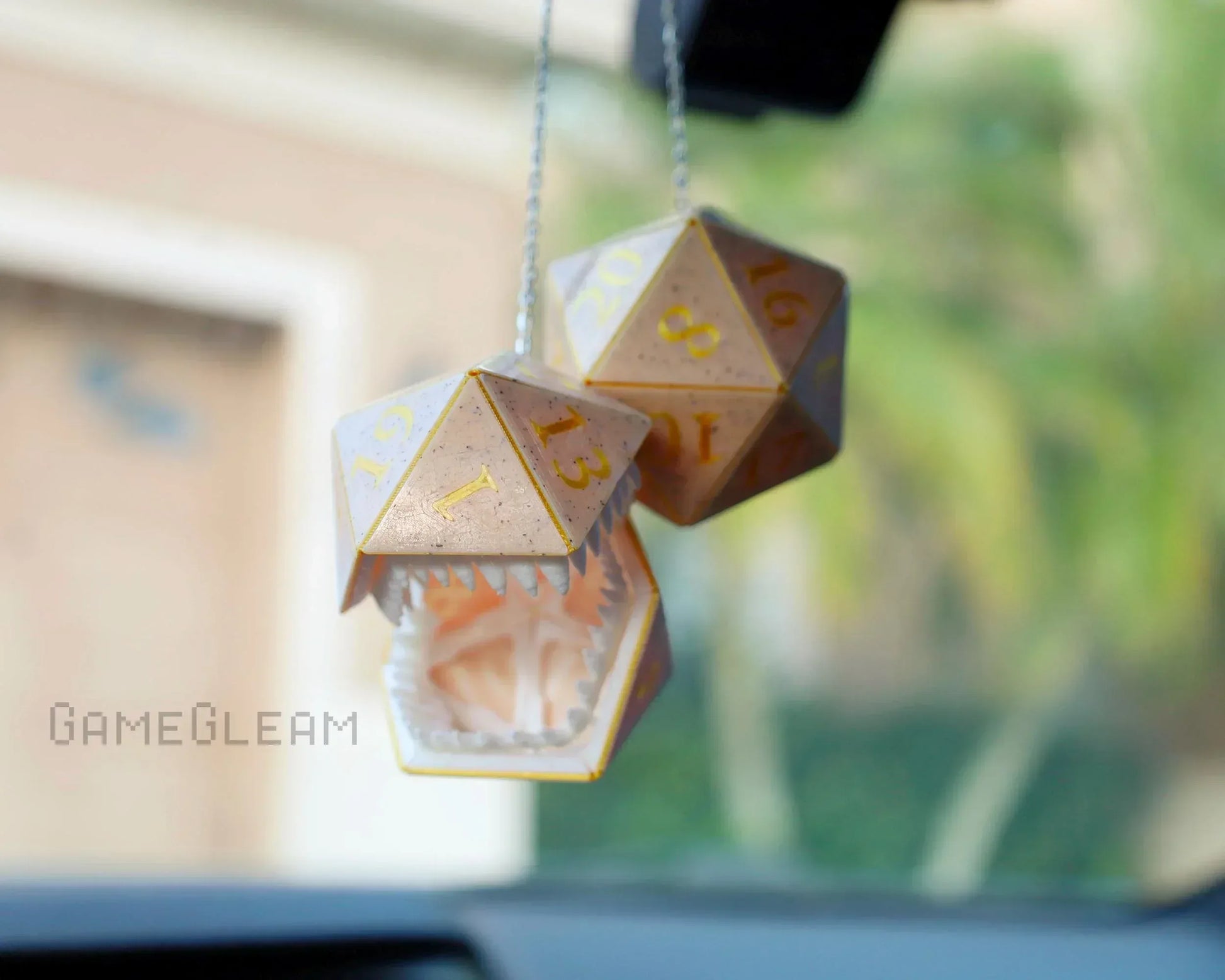 Holographic polyhedral dice car charm with monster mouth, hanging from rearview mirror