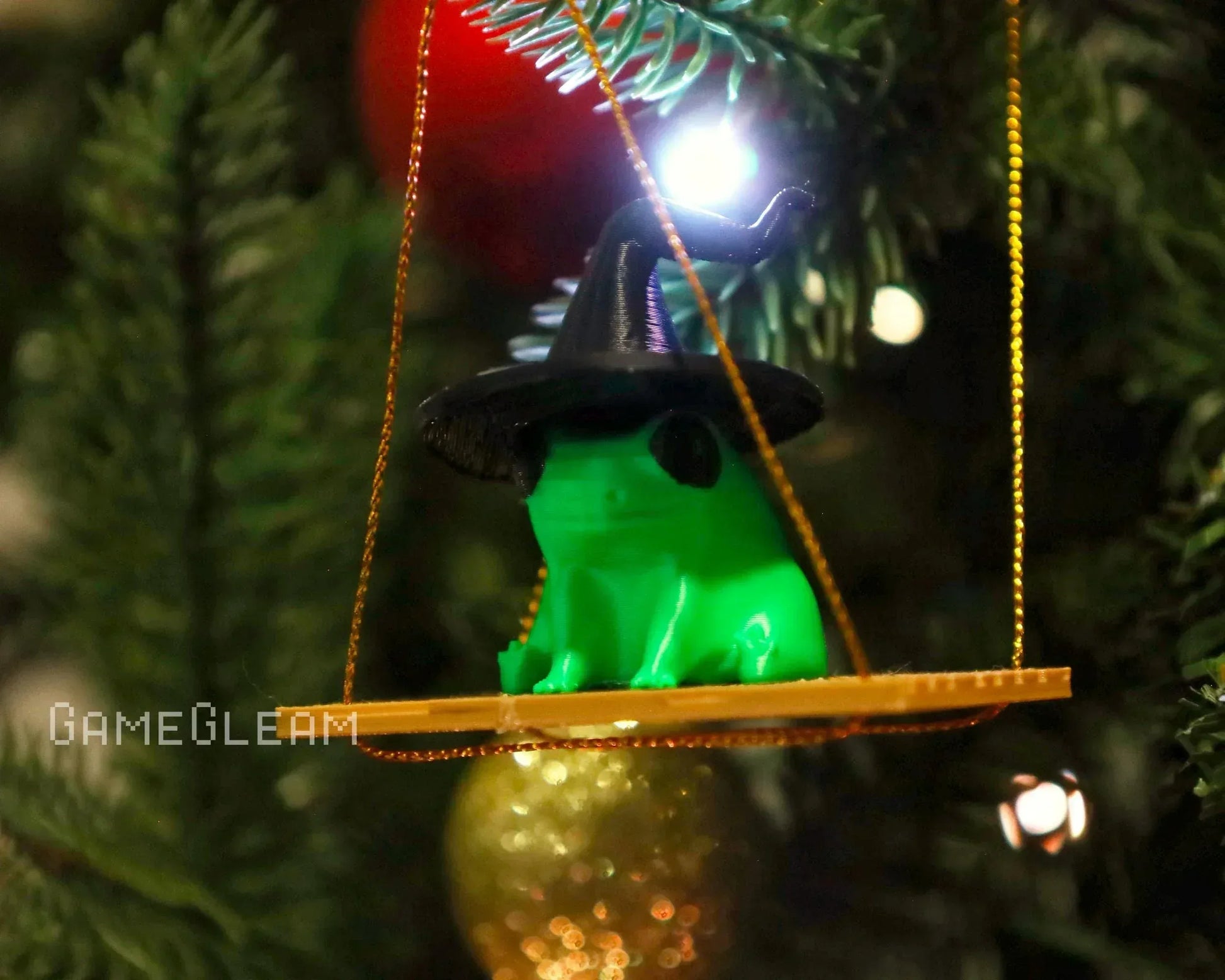 Green frog figurine in a wizard hat ornament, hanging on a Christmas tree branch