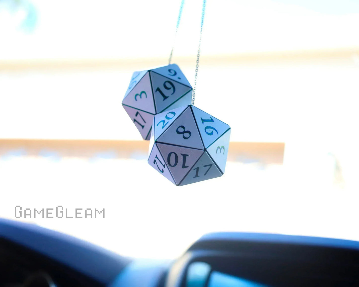 Holographic twenty-sided dice hanging as car mirror charms, sunlight reflecting off surface