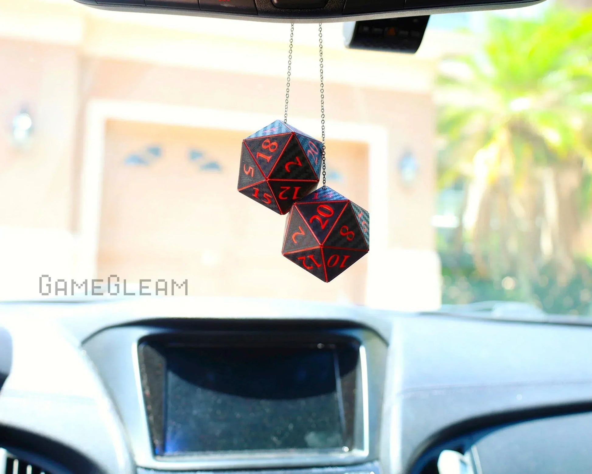 Pair of black and red twenty-sided dice car charms hanging from rearview mirror inside vehicle