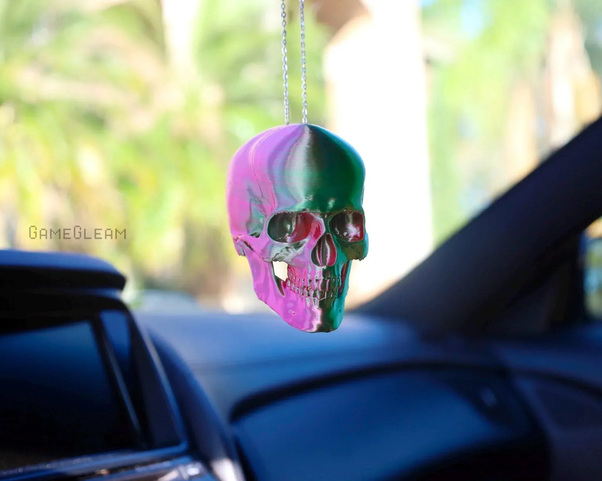 Holographic pink and green skull car charm hanging from rearview mirror