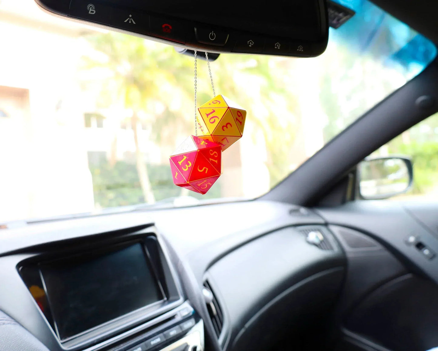 Holographic twenty-sided dice car charm hanging from rearview mirror in car interior