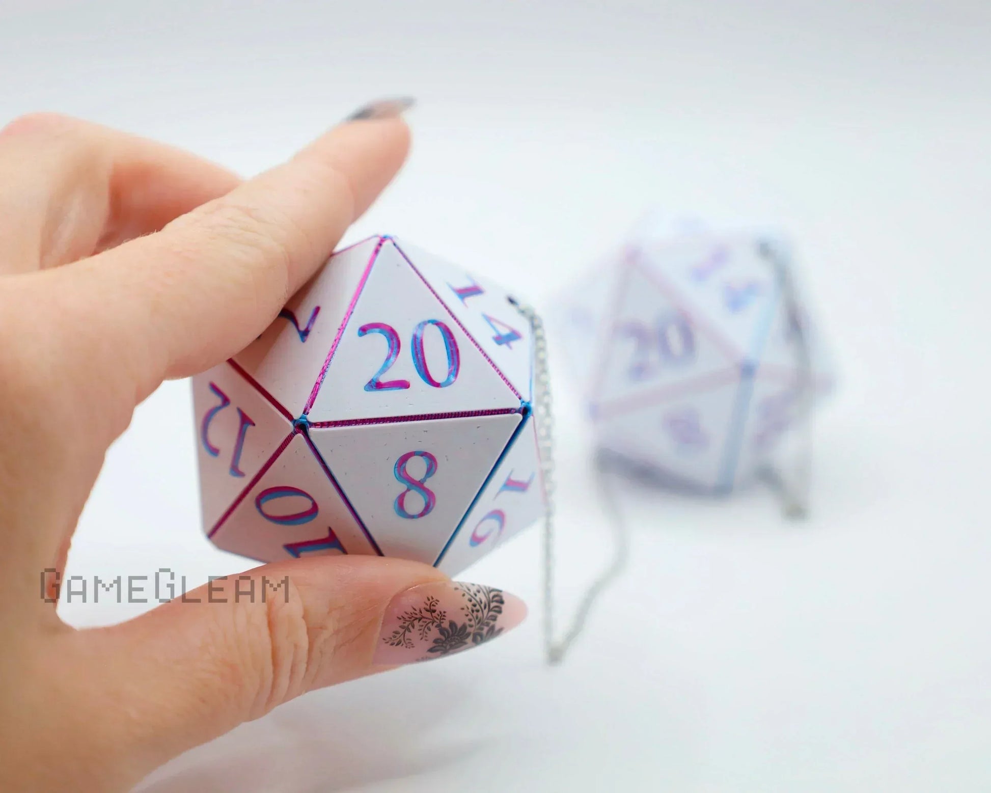Hand holding a holographic twenty-sided dice car accessory with metallic numbers on a chain