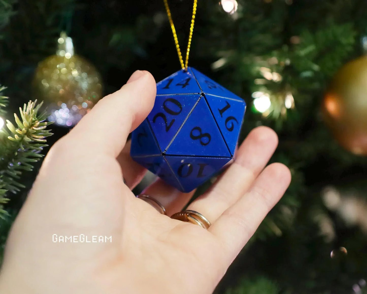 Blue 20-sided dice ornament held in hand, hanging on a Christmas tree