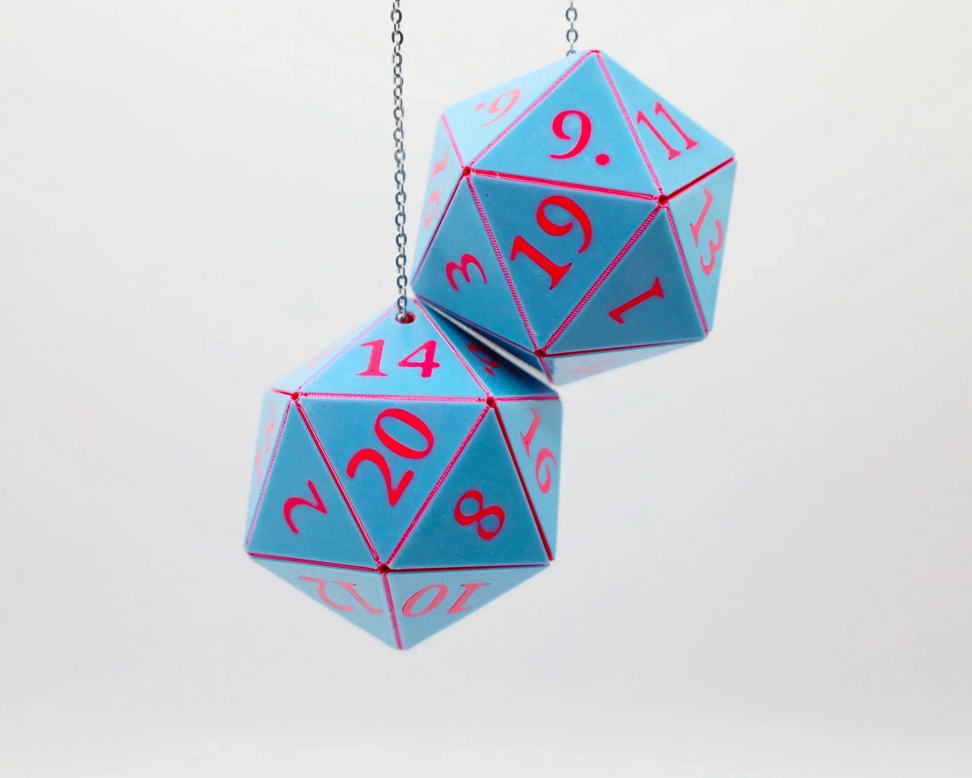 Pair of blue twenty-sided dice with pink numbers hanging on silver chain, tabletop gamer decor