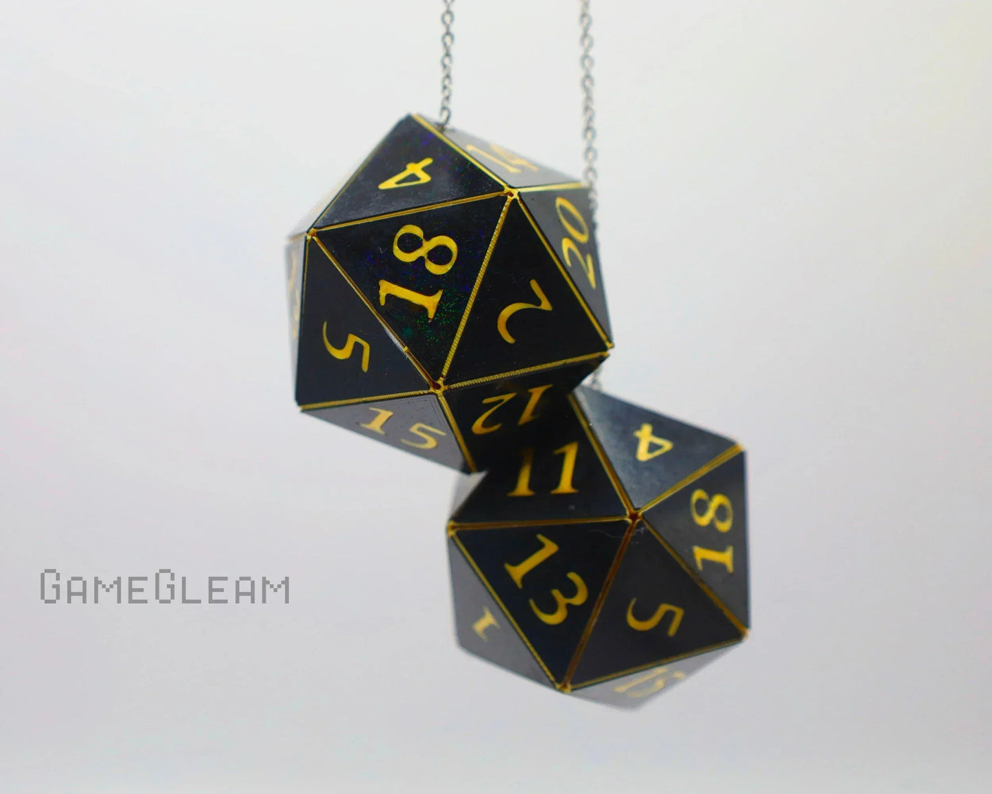 Black and gold twenty-sided dice hanging as car dice charm on a chain, white background