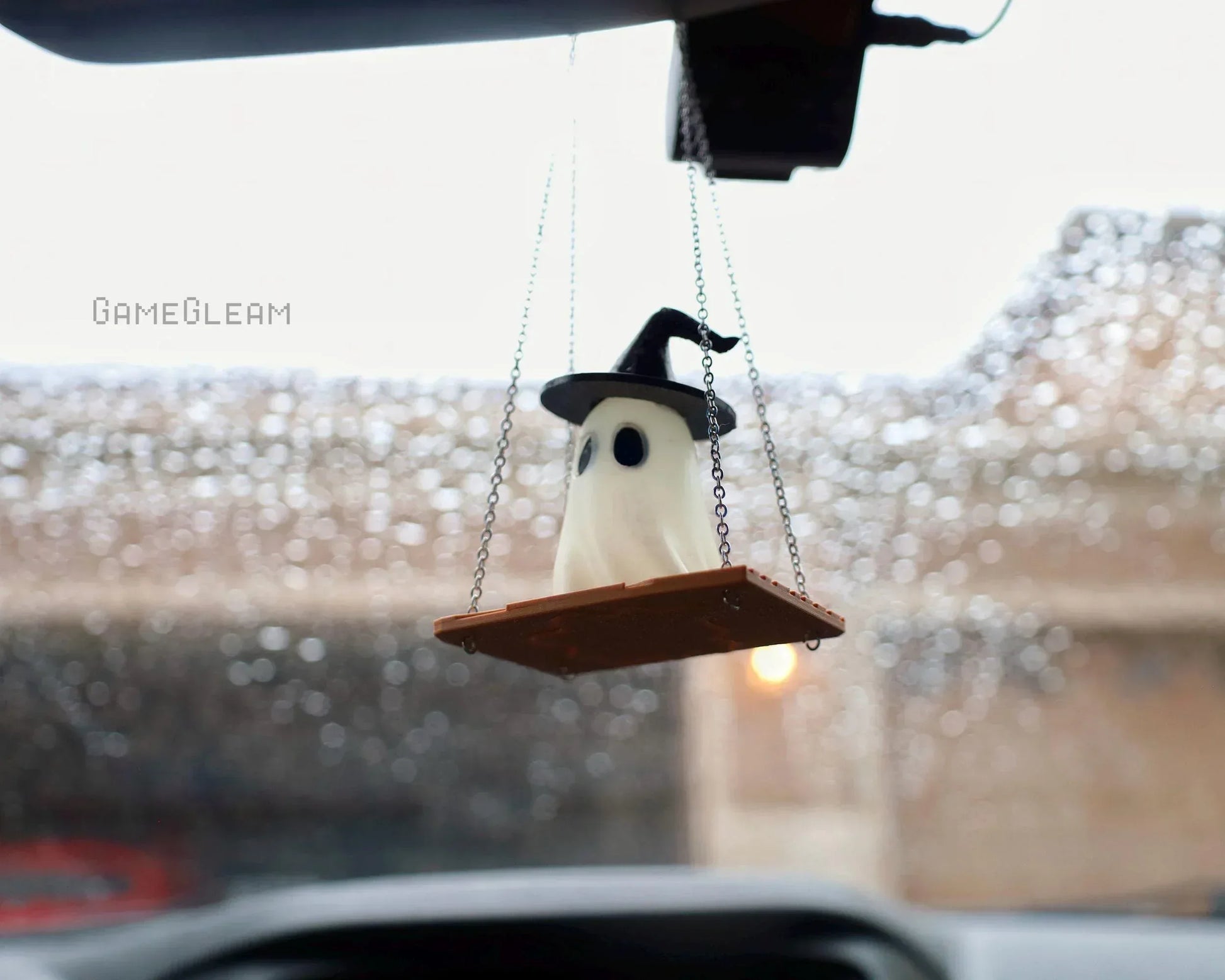 Handmade ghost car charm with witch hat on swing, hanging from rearview mirror.
