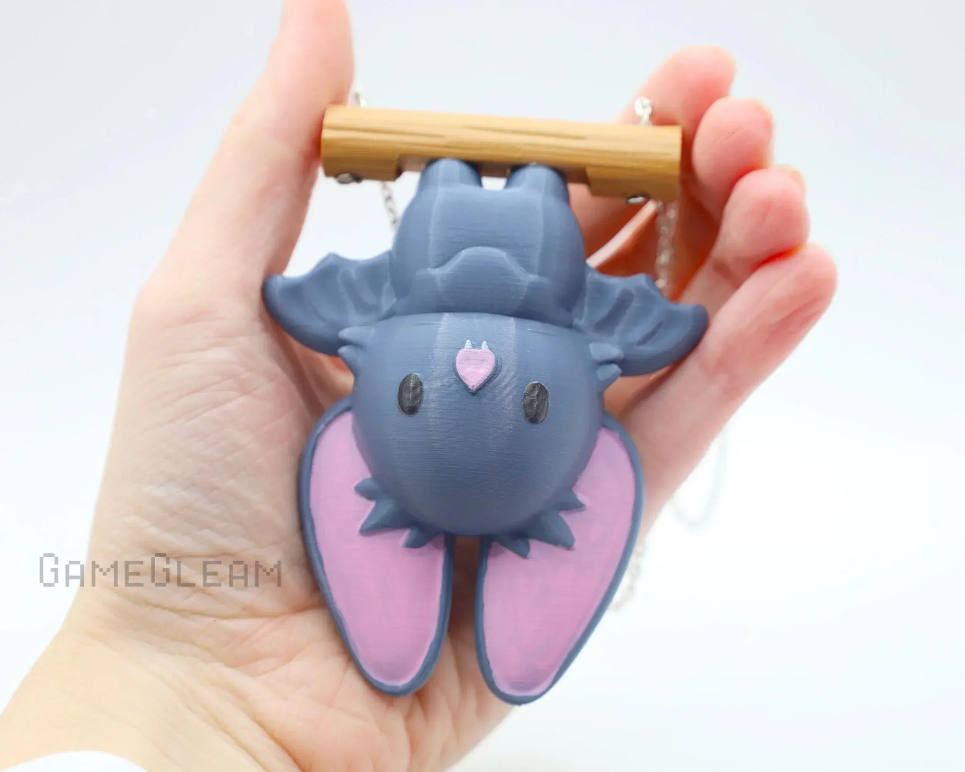 Hand holding a cute handmade bat charm with pink ears and wooden branch, unique car accessory