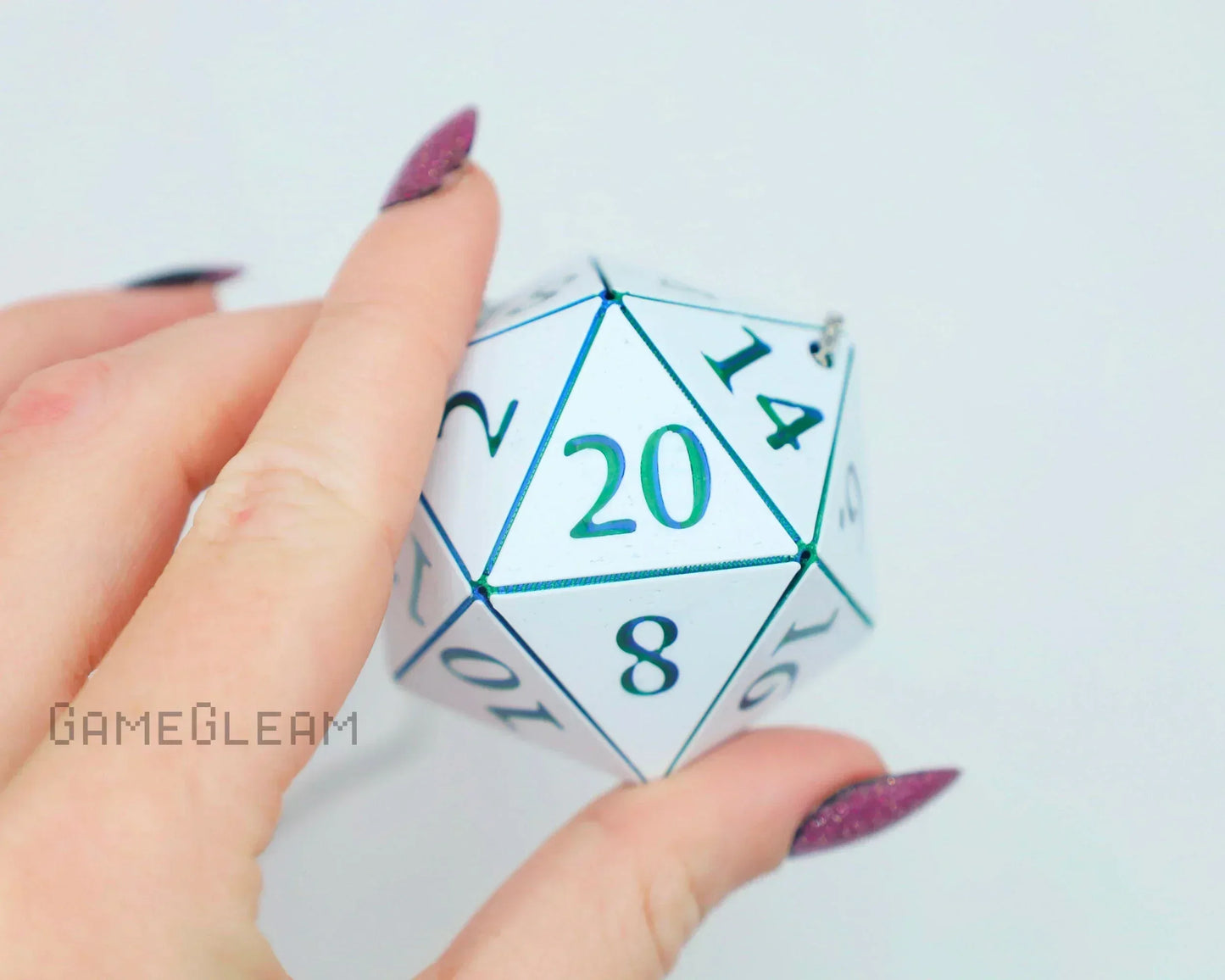 Hand holding a white holographic 20-sided dice charm with teal numbers, gamer accessory