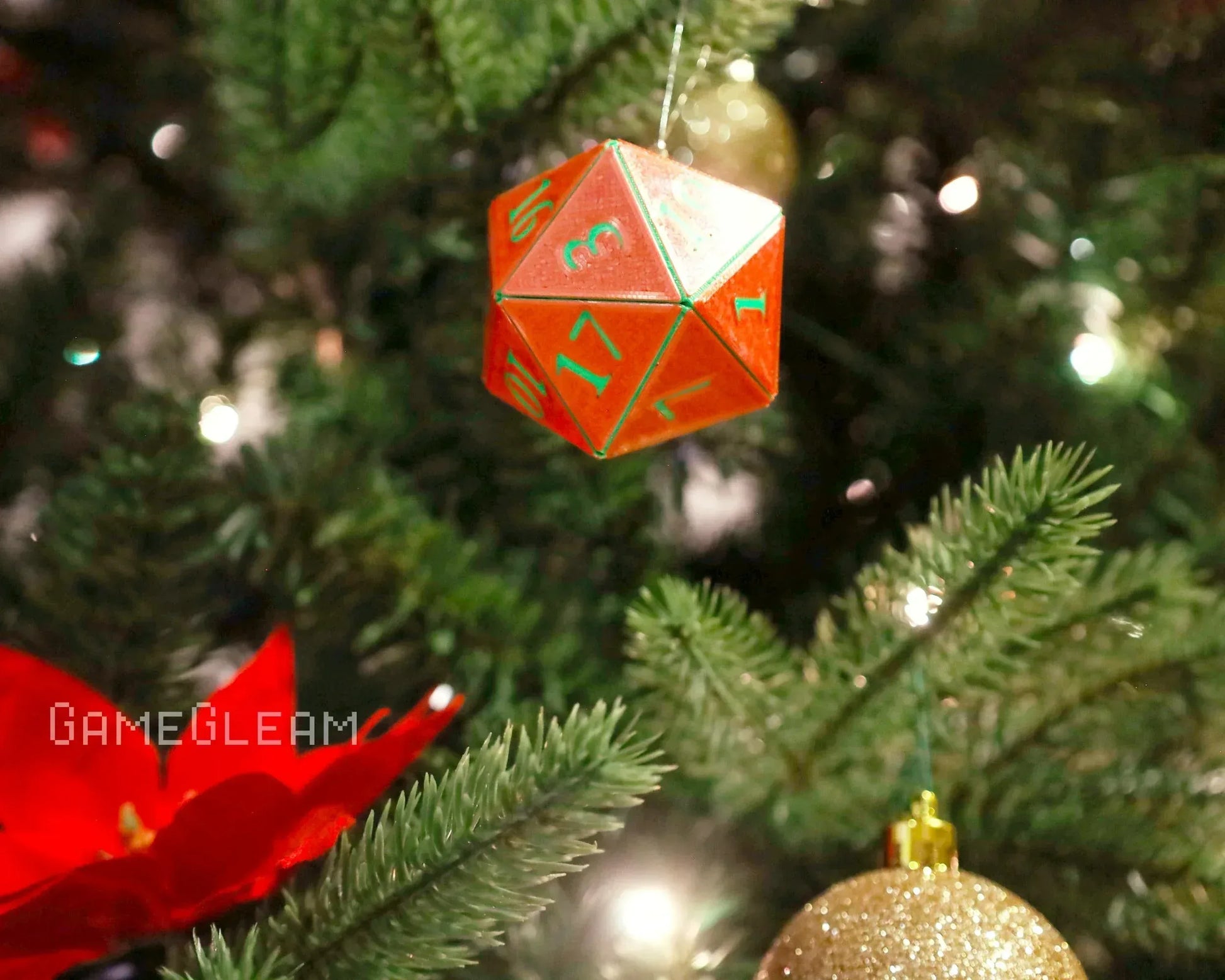 Red holographic twenty-sided dice ornament hanging on a decorated Christmas tree.