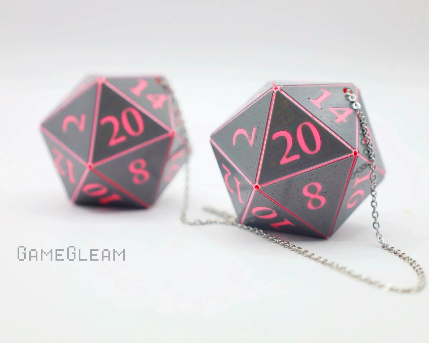 Handmade pink and black 20-sided dice car charms with silver chains on white background