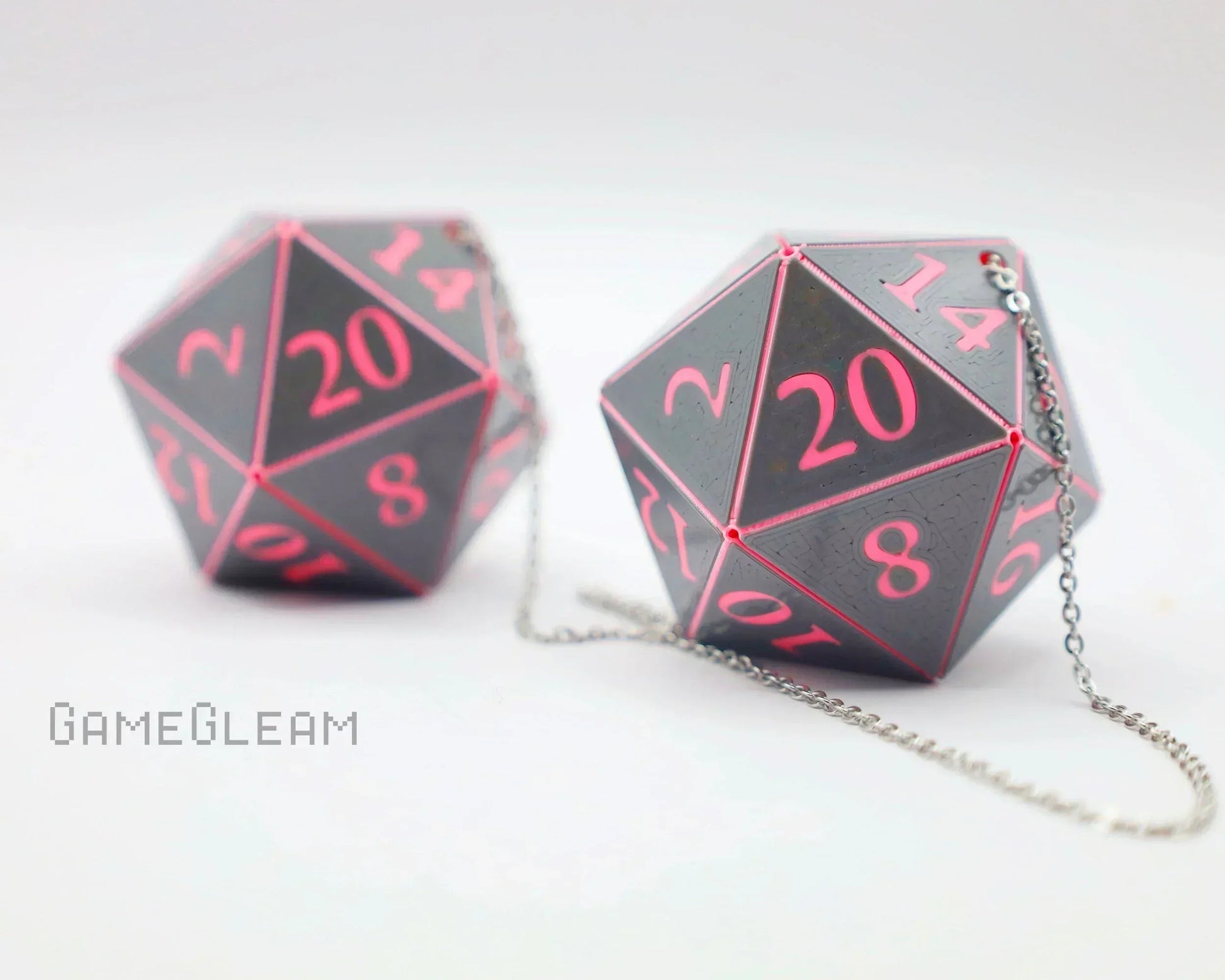 Handmade pink and black 20-sided dice car charms with silver chains on white background