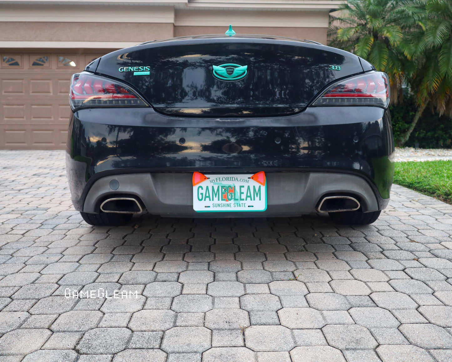 Black Genesis coupe with custom Florida license plate reading GAMEGLEAM, parked on pavers.