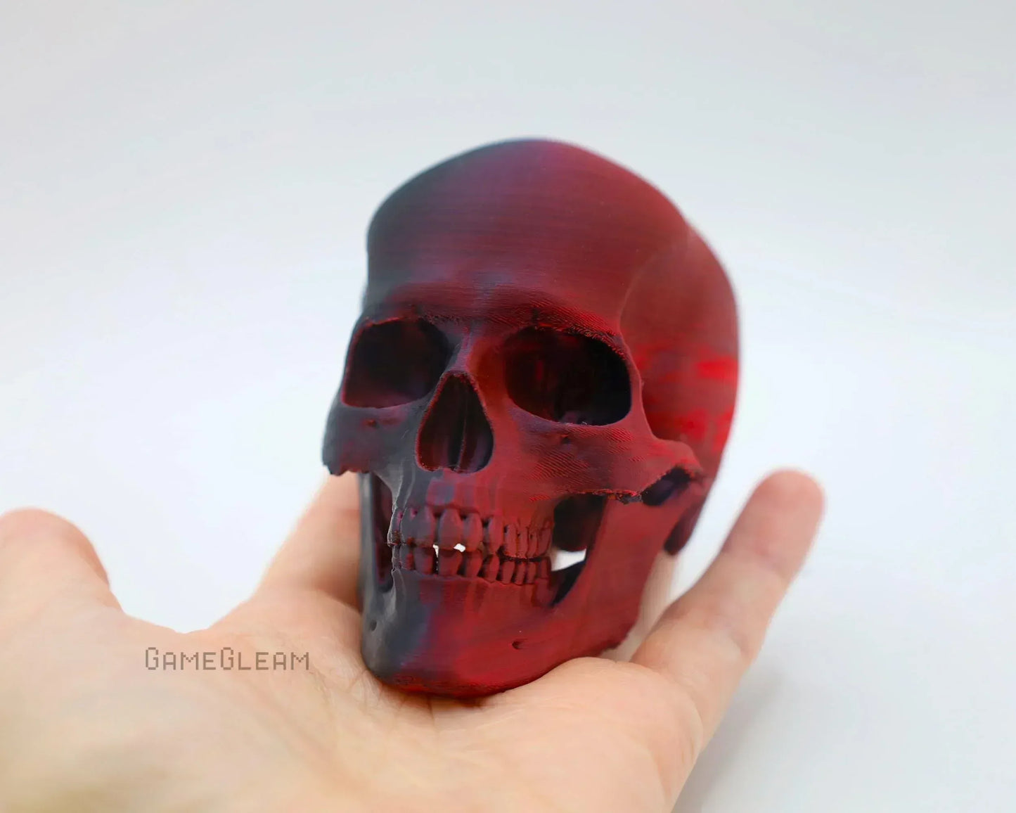 Red and black resin skull decor held in a hand, handmade gamer gift accessory