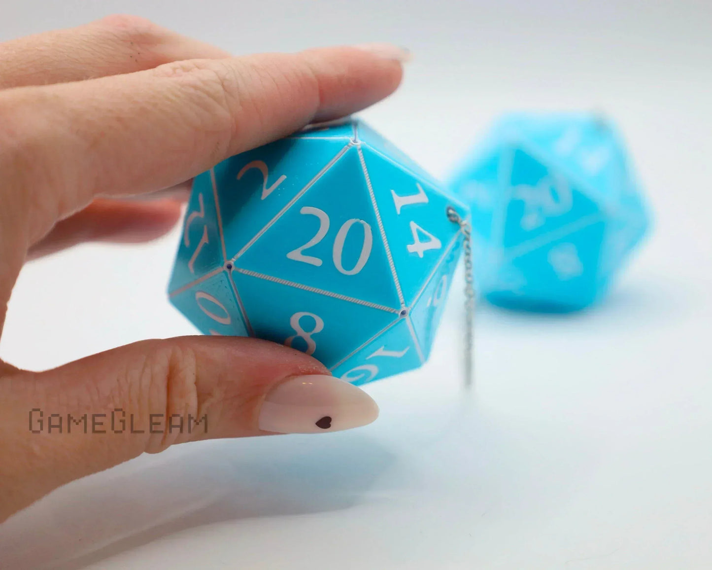 Hand holding large blue 20-sided dice charm with white numbers, ideal for RPG car accessory