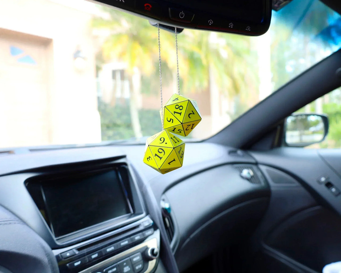Yellow twenty-sided dice car mirror charm in modern vehicle interior