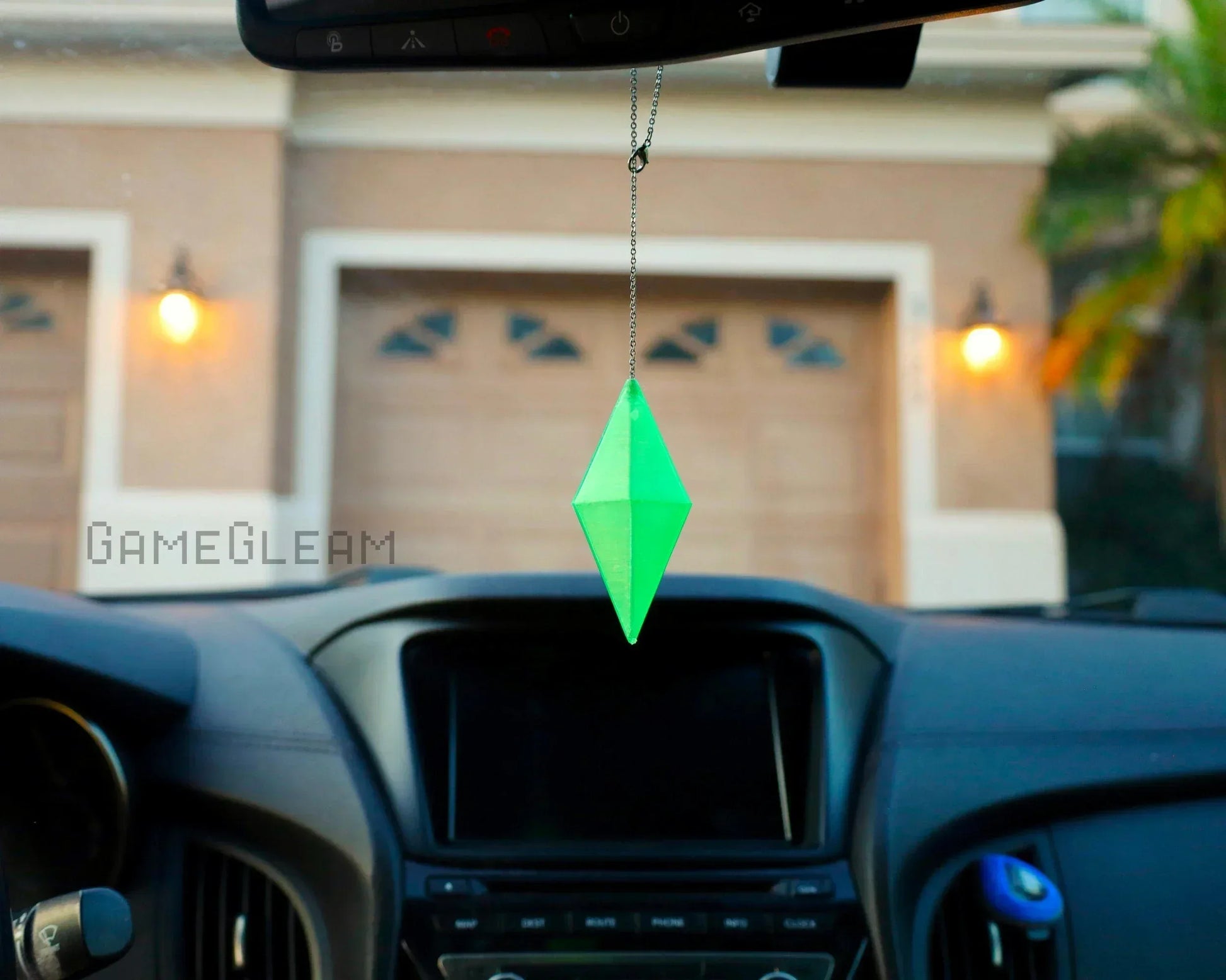 Green geometric crystal car charm hanging from rearview mirror inside a vehicle