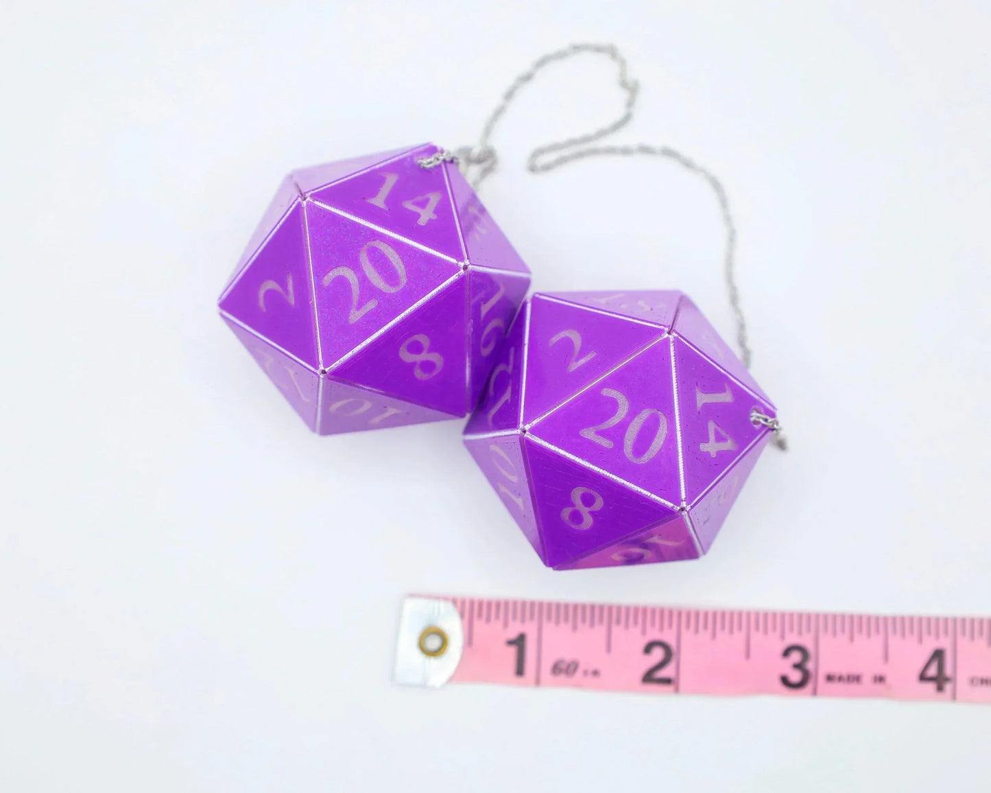 Purple 20-sided dice car charm set with silver chain, shown next to a measuring tape