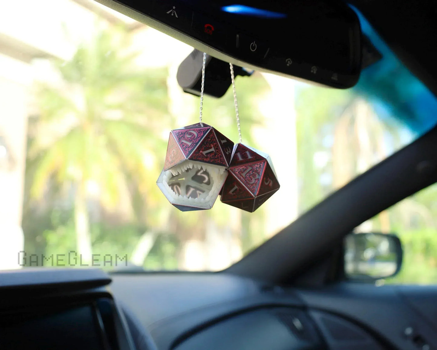 Handmade red and silver polyhedral dice car charm with monster mouth detail, hanging in a car