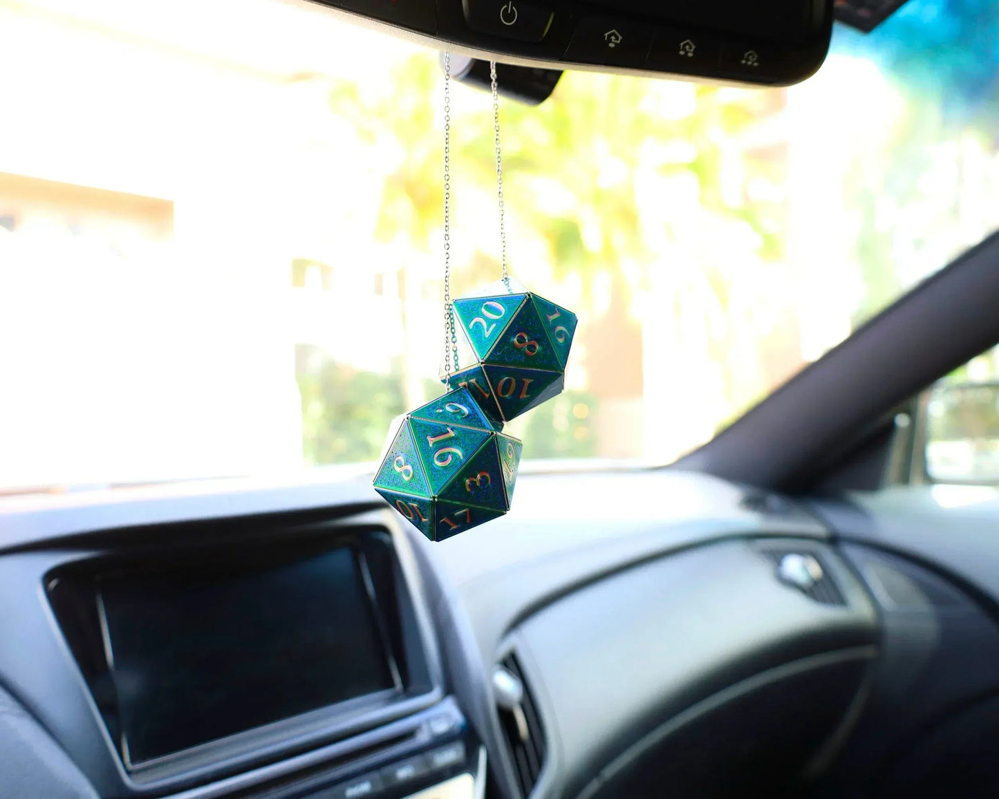 Holographic twenty-sided dice charms hanging from a car rearview mirror, gamer accessory