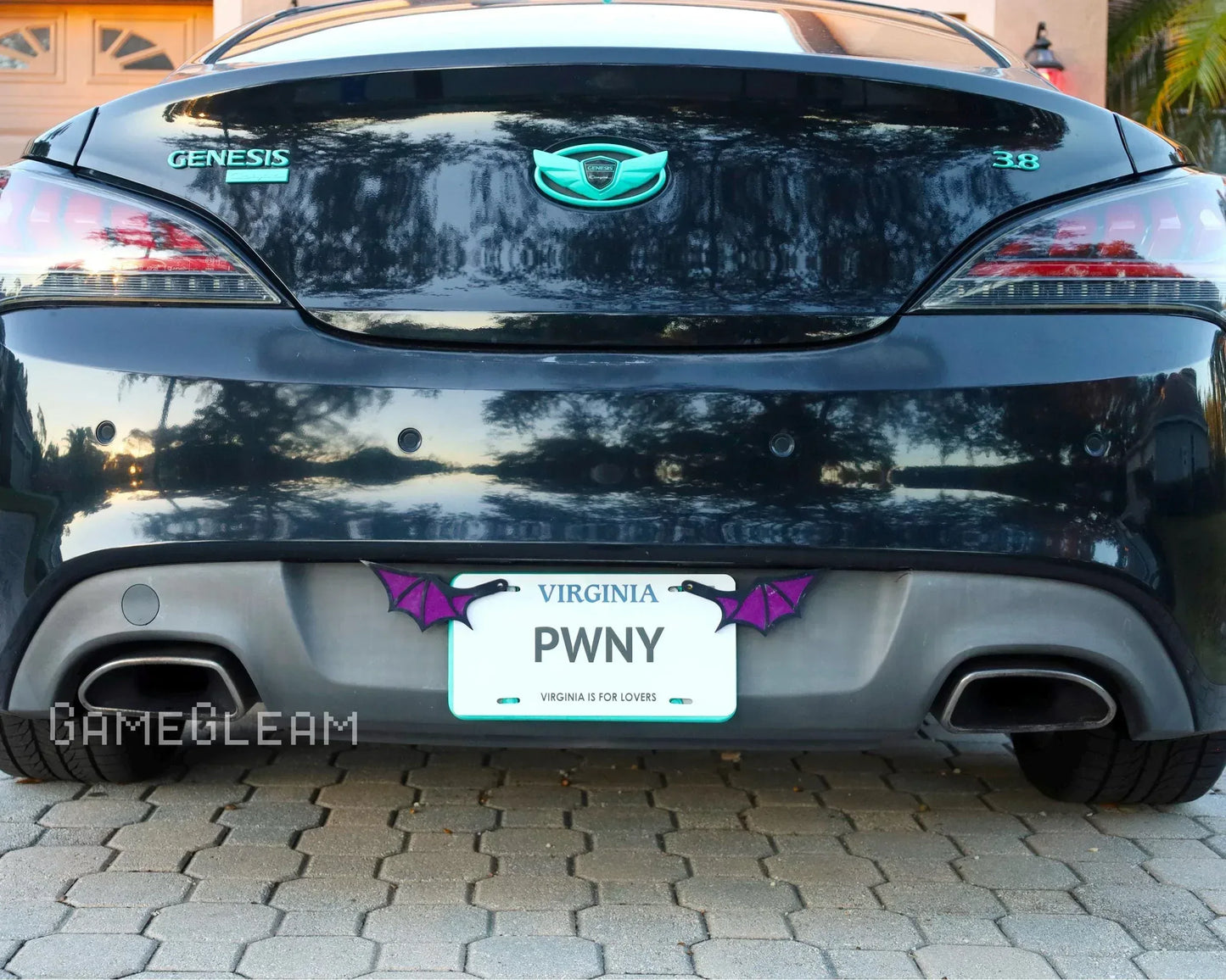 Rear view of a black Genesis car with custom license plate holder featuring purple bat wings.