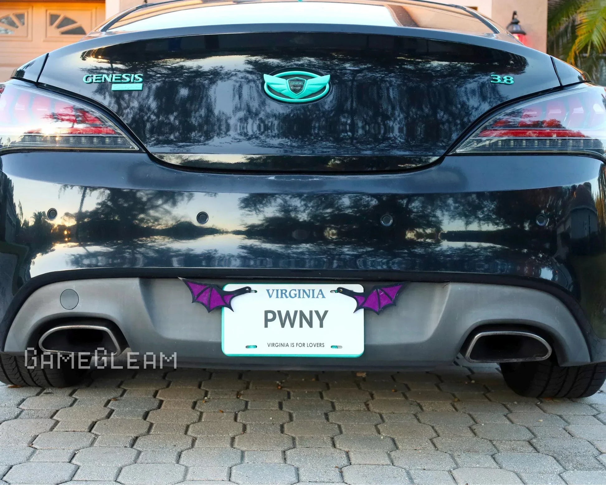 Rear view of a black Genesis car with custom license plate holder featuring purple bat wings.