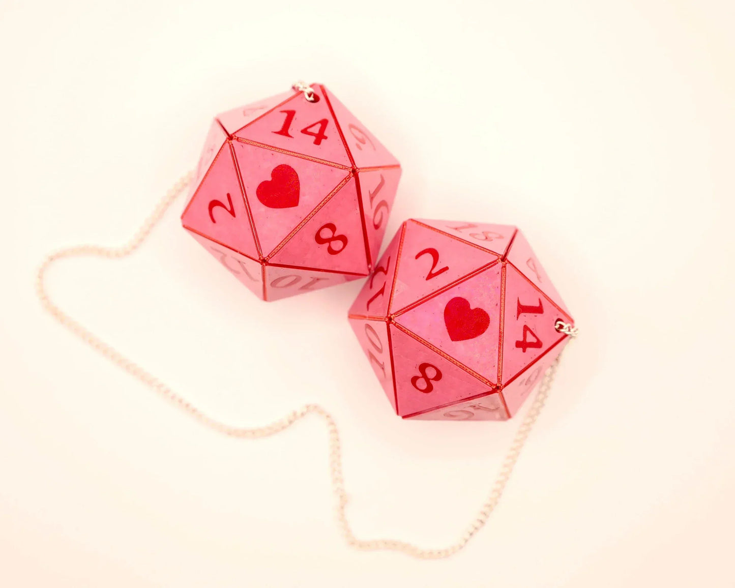 Pink twenty-sided dice with red numbers and heart symbols on a chain, gamer car charm.