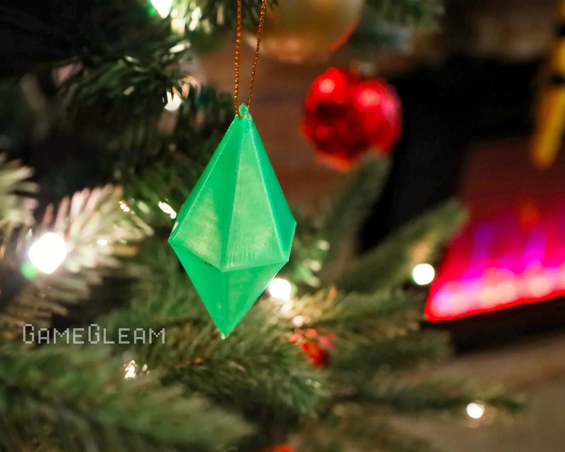 Green geometric ornament hanging on a Christmas tree with festive lights