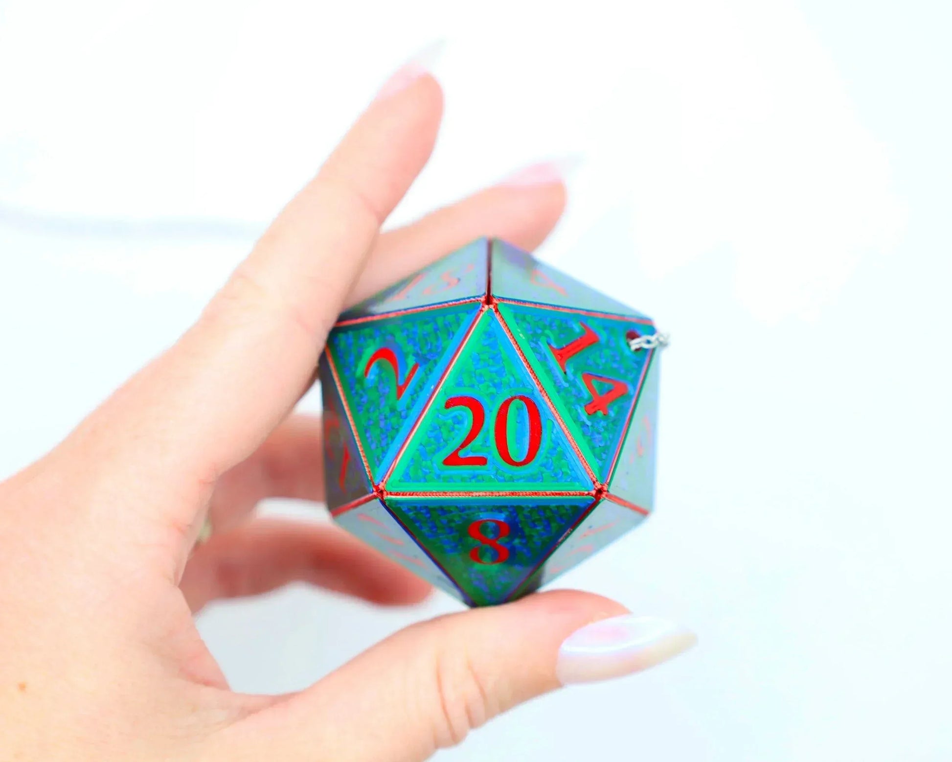 Hand holding holographic 20-sided dice charm with red numbers for tabletop gaming fans