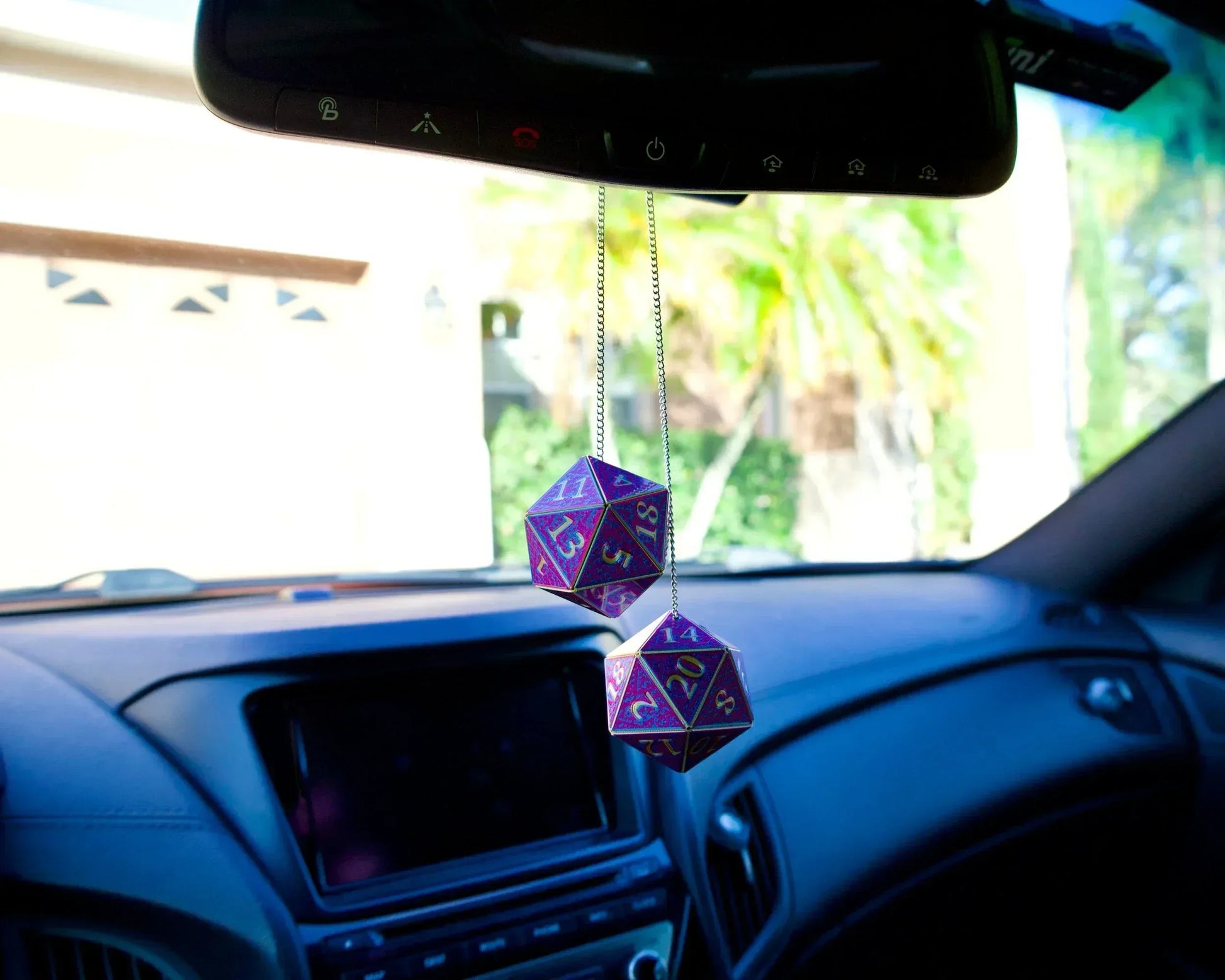 Holographic purple polyhedral dice car charm hanging from rearview mirror in vehicle interior