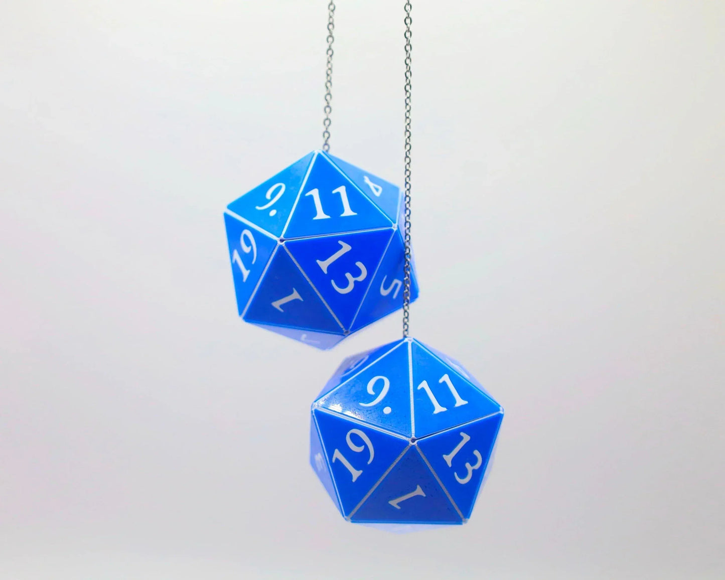Pair of blue 20-sided dice car charms with white numbers hanging from a chain